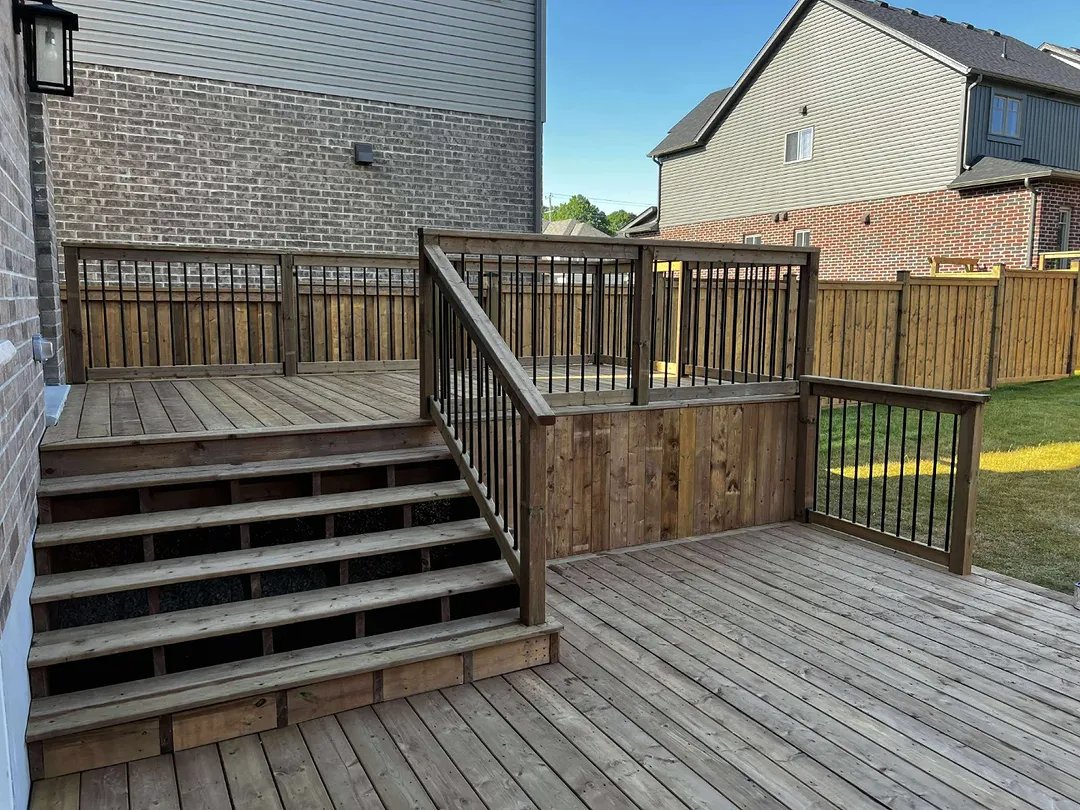 A split level deck with stairs and black picket railing